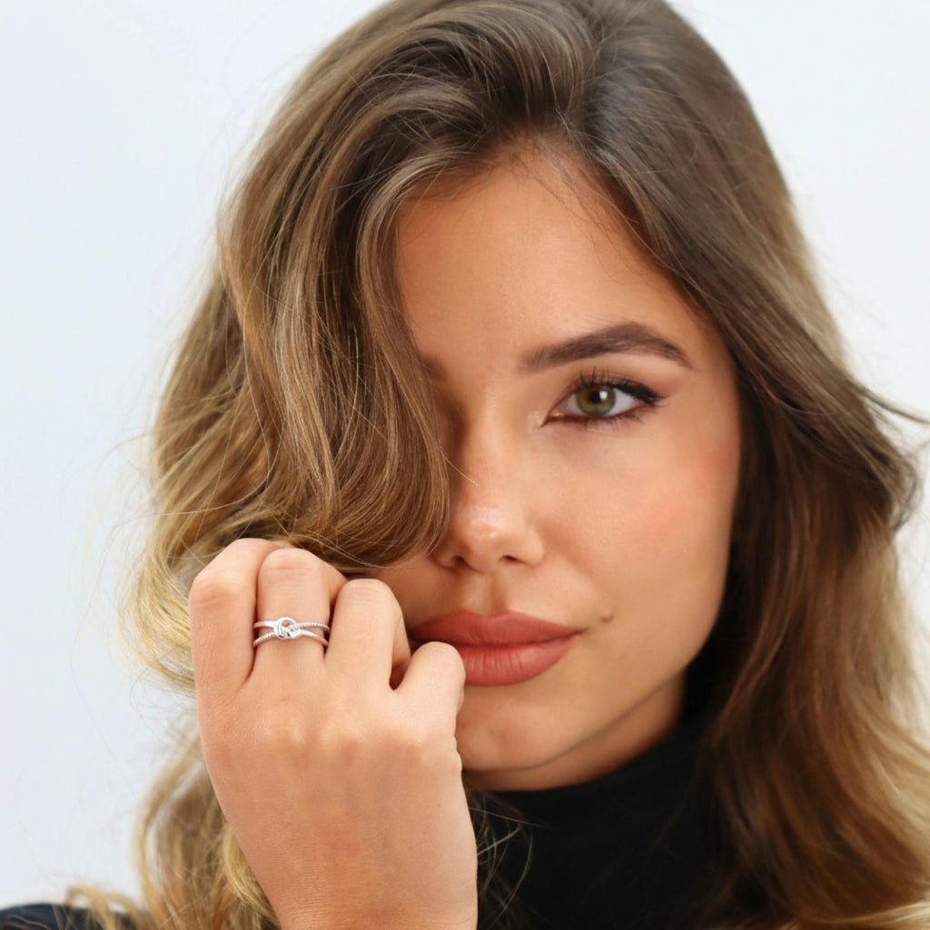 Lifestyle shot of woman wearing Satinski Dainty Adjustable Open Knot Ring in sterling silver.