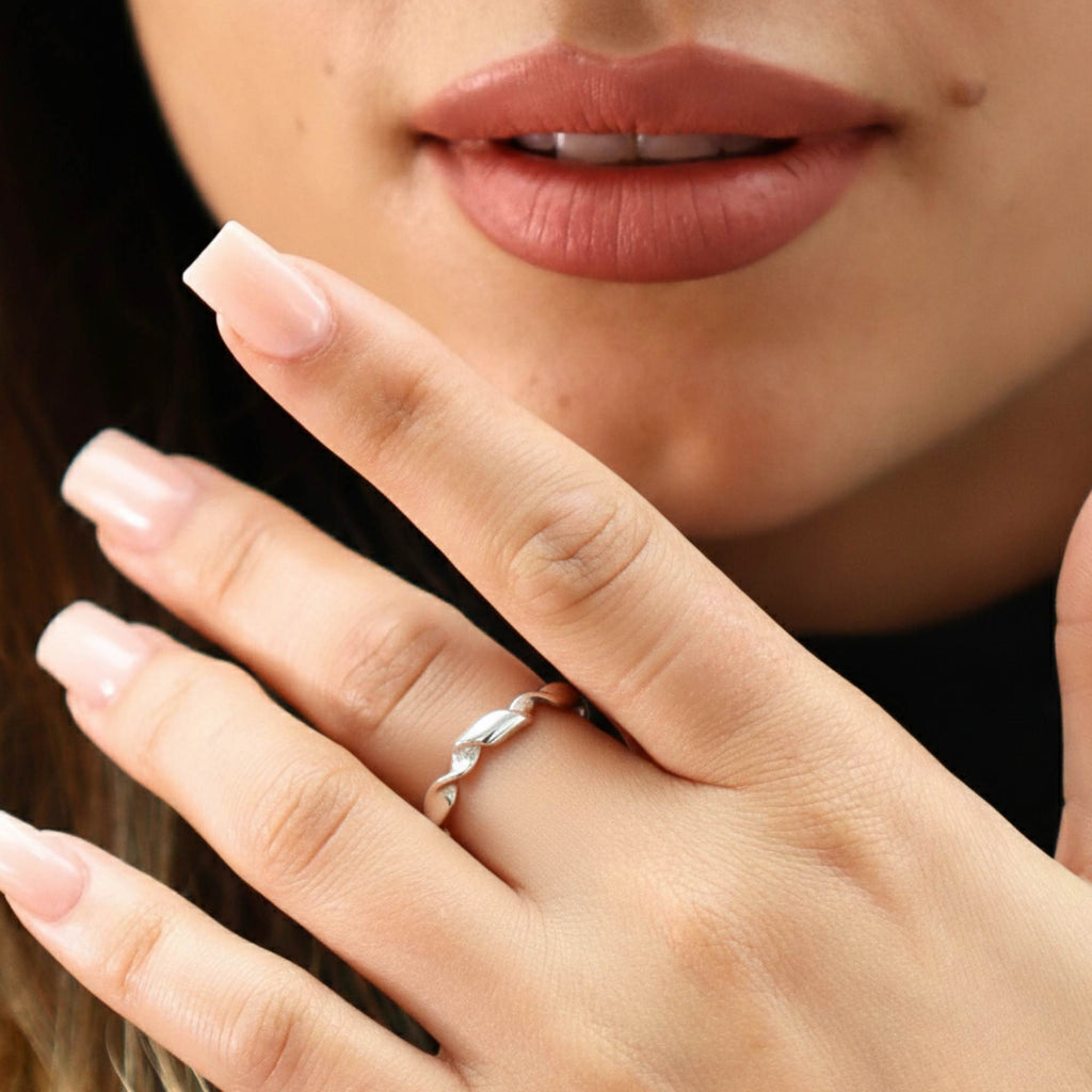Close-up of a hand with an open adjustable resizable ring by Satinski silver ring on a blurred background