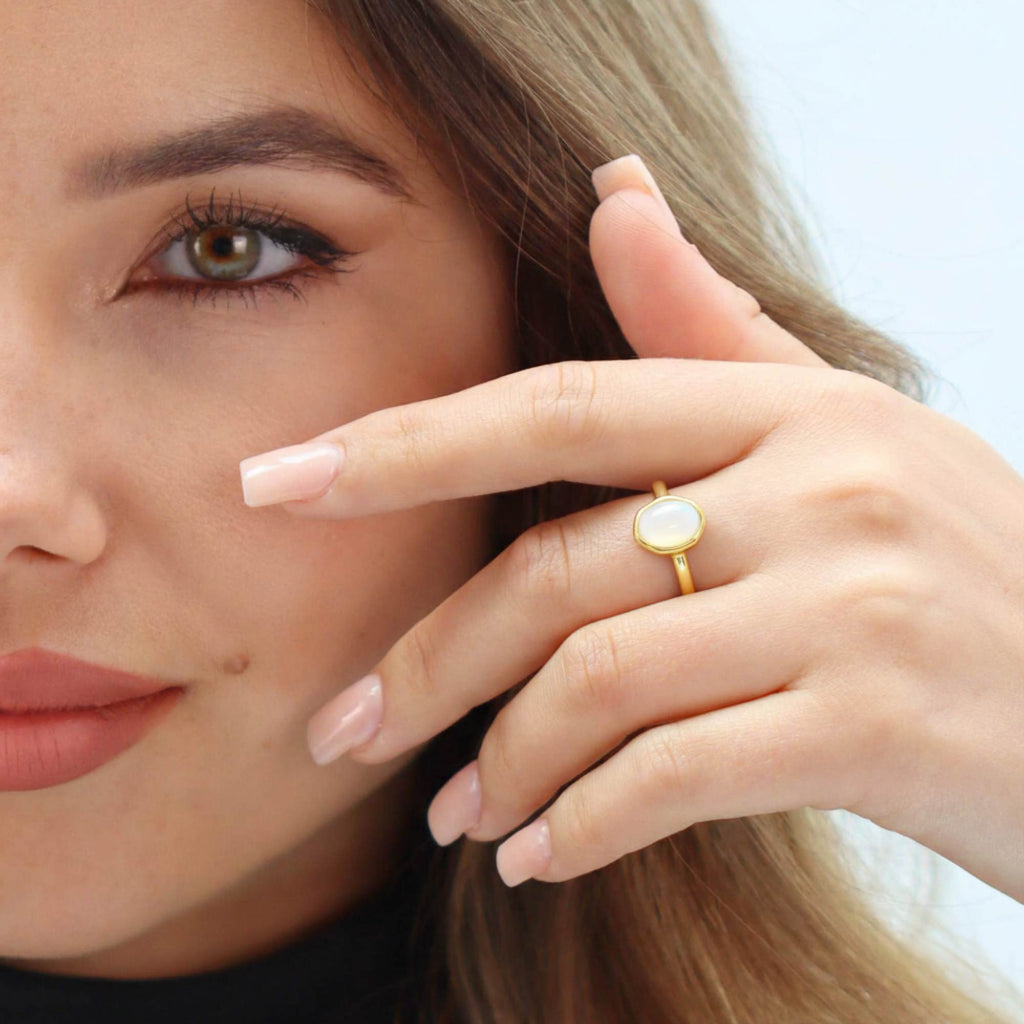 Woman wearing Satinski dainty adjustable open opal ring in gold, close-up on hand near face.